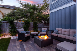 An outdoor garden decked patio with a fire pit and lounge area