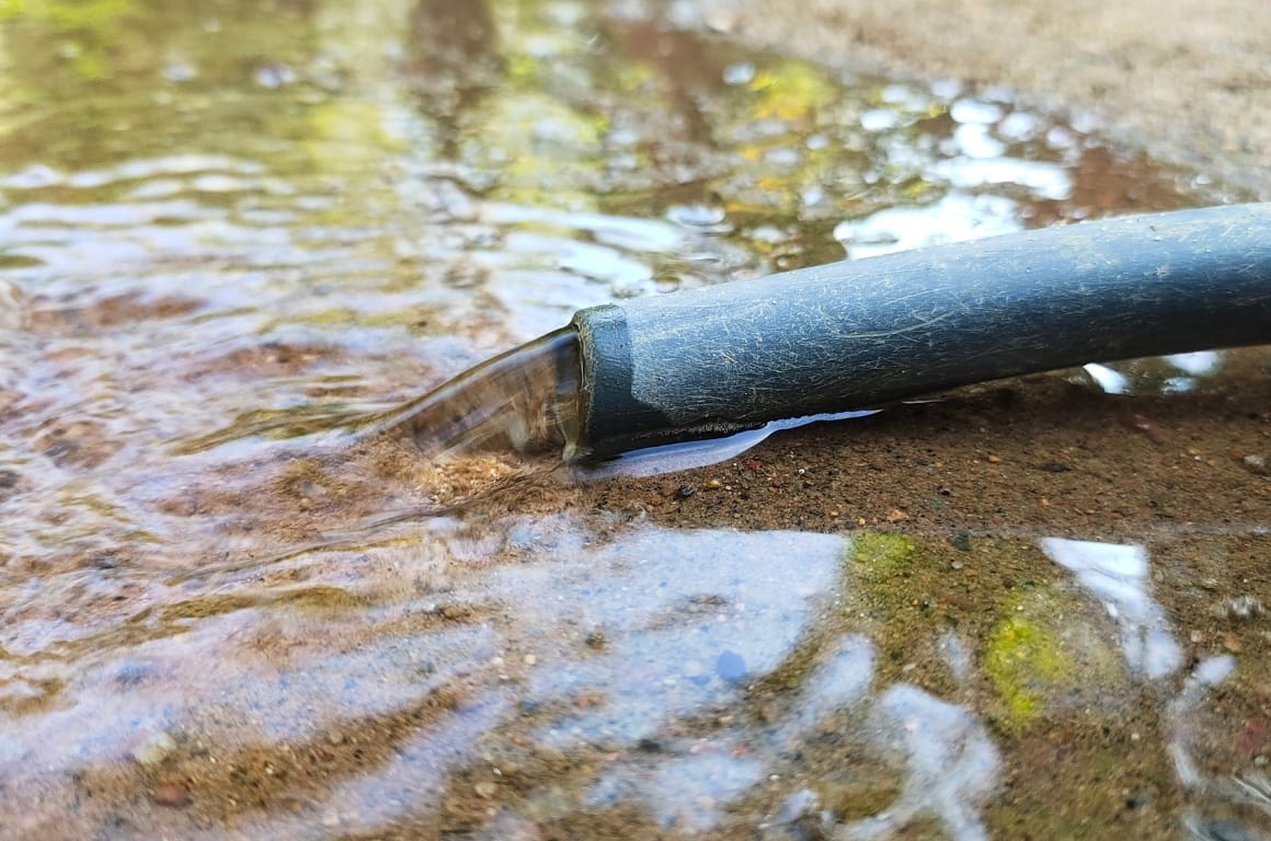 A hosepipe, the connector having popped off, is leaking water onto the floor.